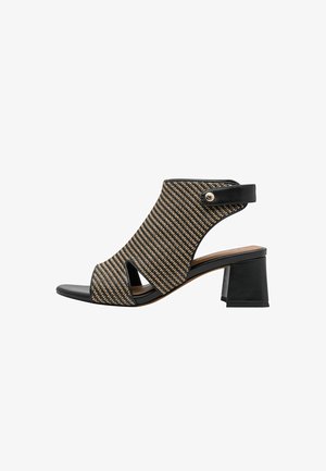 Sort åben tå hælet sandal med vævet beige og sort overdel, udskåret design og ankelrem med metallisk knapdetalje.