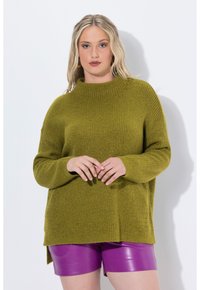 Maglione lavorato a maglia verde oliva con collo alto e vestibilità ampia, abbinato a pantaloni corti lucidi viola. Presenta spacco laterali per maggiore comfort.