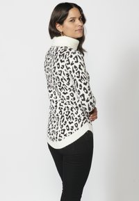 Leopardtryckt tröja i svart och vitt med en ribbad polokrage och rundad nederkant, i kombination med svarta jeans. Mjuk tröja i stickad textur.