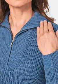 Blauer Strickpullover mit hohem Kragen und Reißverschluss, ausgestattet mit strukturierten Mustern und gerippten Bündchen. Das Material wirkt weich und gemütlich.