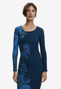 Langärmliges Kleid aus dunkelblauem Rippstoff, mit einem bunten Blumenmuster in Blau- und Schwarztönen auf einer Seite.
