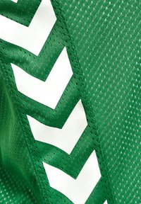 Groen gaasstof met een gestructureerd patroon, met grote witte chevronontwerpen langs één rand. Het materiaal lijkt ademend en licht van gewicht.