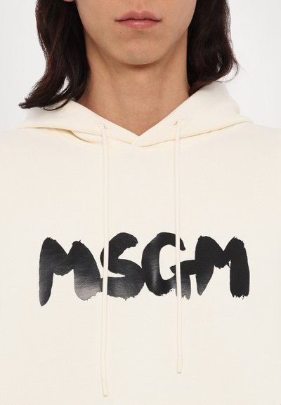 Felpa crema con cappuccio e cordini, caratterizzata da un grande logo "MSGM" in nero a pennellate centrato sul davanti. Tessuto morbido e strutturato.