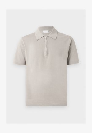 Tricou polo bej cu mâneci scurte, cu guler ascuțit și închidere frontală cu fermoar pe jumătate, afișat pe un fundal simplu.