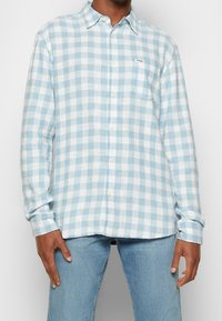 Ljusblå och vit rutigt långärmad skjorta i ett mjukt tyg med knapp-down krage och en vänster bröstficka.