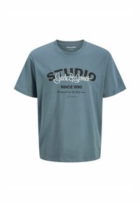 Plava kratki rukav majica s okruglim izrezom, s natpisom "STUDIO Jack & Jones SINCE 1990 Dizajnirao J&J tim" otisnutim sprijeda.