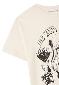 Maglietta in cotone color crema con design grafico nero che presenta il testo "BE KIND", fiamme e un'illustrazione di un personaggio. Maniche corte, vestibilità classica.