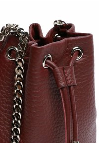 Borsa bordeaux in pelle con coulisse, superficie testurizzata, dettagli in metallo argento e tracolla a catena. Presenta occhielli metallici per la chiusura.