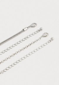 Τρία ασημένια επεκτατικά κολιέ αλυσίδας με κλιπ αστακού και σφαιρικά άκρα σε λευκό φόντο.