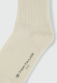 Beige ribbattu sukkaset, joka on valmistettu kankaasta. Sukassa on painettu logo "TOM TAILOR" sekä koko "35-38" pohjassa. Sujuva pinta, jossa on pehmeä viimeistely.