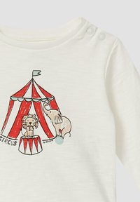 Lichtroom shirt met een illustratie van een rood en wit gestreepte circus tent, met een leeuw op een trommel en een olifant. Drukknoopsluiting bij de hals.