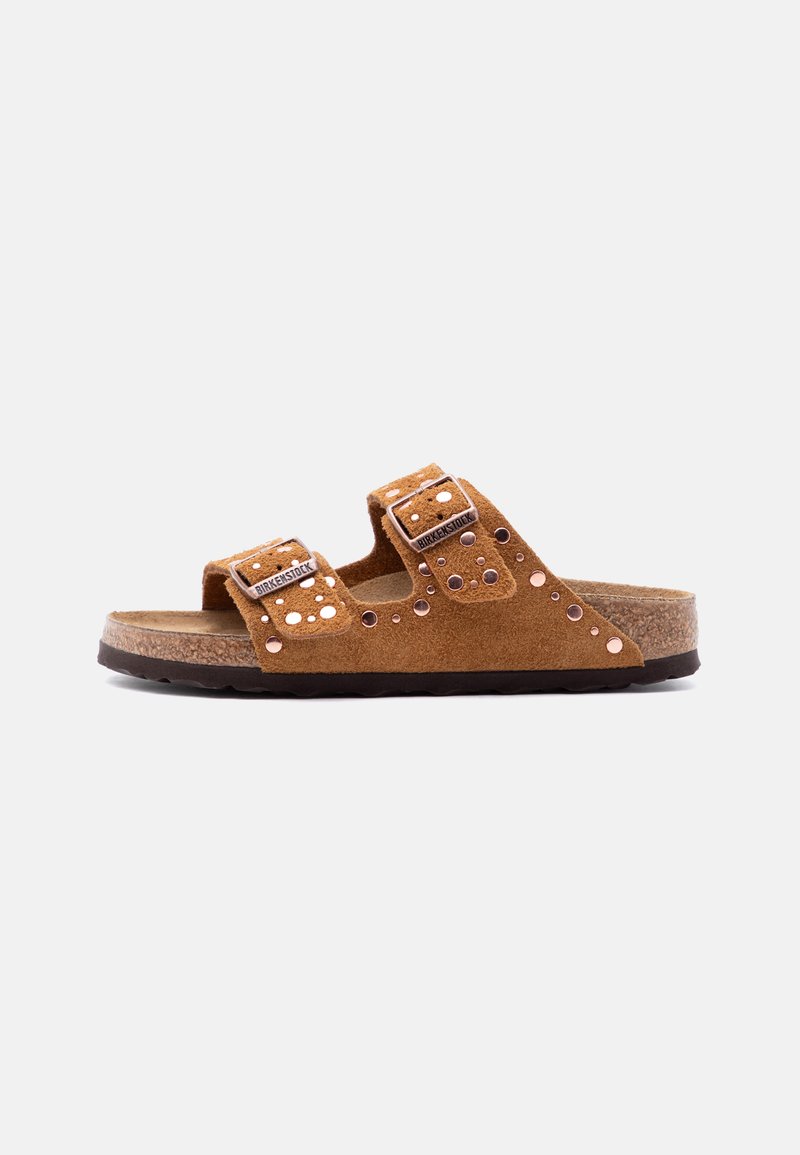 Καφέ σουέντ σανδάλι Birkenstock με δύο ρυθμιζόμενους ιμάντες με αγκράφες και μεταλλικά τρουκς σε σόλα από φελλό και μαύρη σόλα με πέλμα.