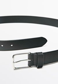 Sort læderbælte med en glat tekstur, sølvmetal spænde og flere justerbare huller; elegant design med en tilspidset ende.