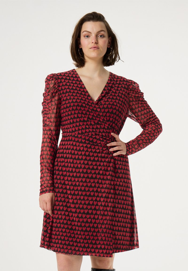 Rotes Wickelkleid mit Herzenmuster, transparenten Ärmeln und V-Ausschnitt. Verfügt über ein tailliertes Oberteil und einen schwingenden Rock, der Bewegung und Form verleiht.