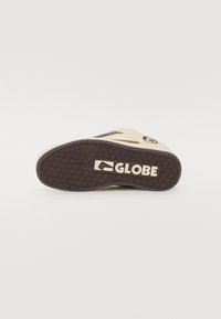 Sneaker sole featuring a textured brown rubber design with a prominent "GLOBE" logo in beige and a cream-colored upper section.