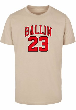 Béžové bavlnené tričko s červeným, tučným nápisom "BALLIN" nad číslom "23". Klasický dizajn s okrúhlym výstrihom a krátkymi rukávmi.