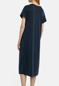 Ciemnoniebieska sukienka do kolan z miękkiej tkaniny, z krótkimi, zwijanymi rękawami i bocznym rozcięciem u dołu dla ułatwienia ruchów.