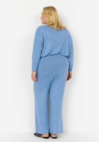 Blå, texturerad jumpsuit med lång ärm, avslappnad passform och vida ben. Mjuk material och enfärgad utan synliga mönster eller detaljer.