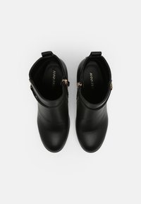 Botines negros de cuero suave con punta redondeada, que presentan un cierre lateral y detalles texturizados en la parte trasera.