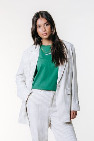 Veste de costume gris clair rayée, associée à une chemise verte avec le texte "COLOURFUL". Pantalon slim complétant la tenue.