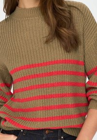 Suéter de punto en verde olivo con rayas horizontales rojas. Presenta un cuello acanalado y mangas anchas. La textura parece gruesa y acogedora.