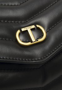 Borsa in pelle nera con un design trapuntato, dotata di una chiusura in hardware dorato incisa con "TWINESET". Tessuto liscio con dettagli cuciti.