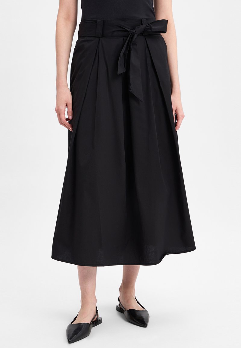 Zwarte plissé midi-rok met een strikceintuur, voorzien van een gladde textuur en een vloeiende silhoeet, aangevuld met puntige slingback schoenen.