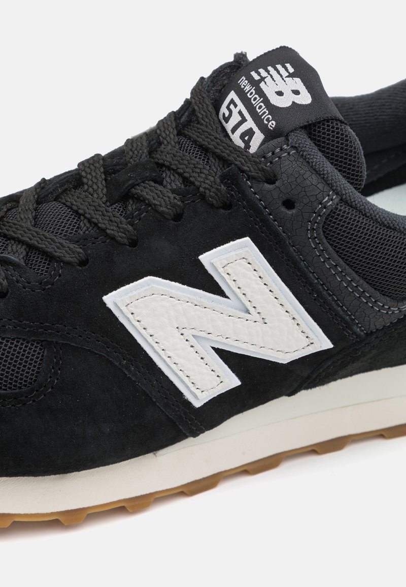 Schwarzer Wildledersport-Schuh mit Mesh-Akzenten. Ausgestattet mit einem weißen Leder-logo "N", strukturierter Zwischensohle und braunem Gummiaußensohle. Modell 574.