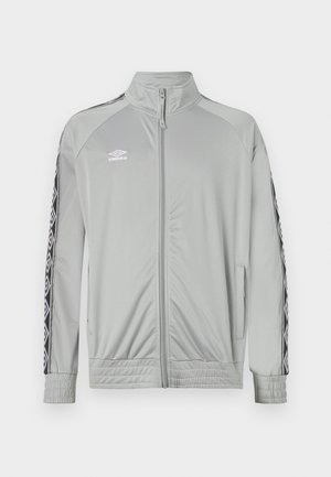 Veste de sport zippée gris clair avec col montant, rayures noires et blanches sur les manches, et logo Umbro sur la poitrine gauche.