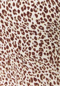 Ruskea ja beige leopardi-kuosisekoitus, jossa on pehmeä rakenne. Esittää epäsäännöllisiä pilkkuja kermaanäytössä ja saumattoman muotoilun.