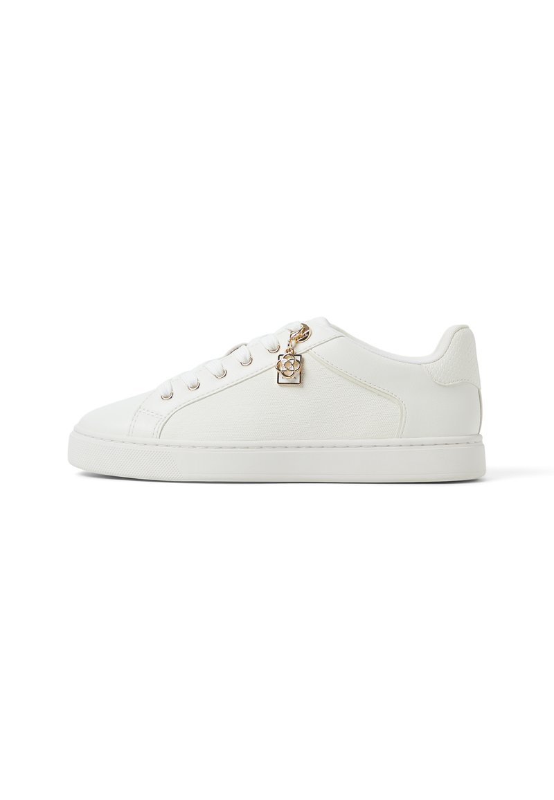 Weiße Sneaker mit strukturiertem Finish, runder Zehenpartie, flacher Gummisohle und goldenem Charme-Detail an der Schnürung. Glattes und modernes Design.
