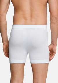 Boxer da uomo bianchi in cotone con una morbida vita elasticizzata, caratterizzati da una texture a coste e un design aderente, visti da dietro.