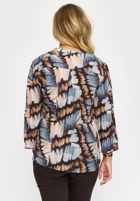 Flerfärgad blus med ett tie-dye-mönster i nyanser av blått, brunt och beige. Tillverkad av lätt material med långa ärmar.