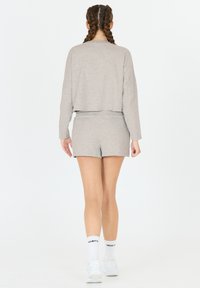 Ljust grå croppad sweatshirt med långa ärmar, matchad med grå shorts, båda i mjukt tyg. Minimalistisk design, inga mönster.