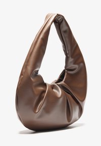Borsa hobo in pelle marrone con una texture morbida e rugosa e un manico allungato e curvo. Presenta un design elegante e minimalista.