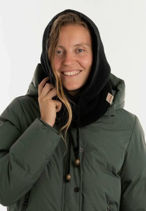 Groene gewatteerde jas met een zwarte gebreide capuchon. Voorzien van houten toggles en een zachte textuur, die warmte en comfort biedt.