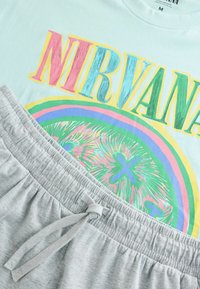 Tricou light blue cu grafică multicoloră "NIRVANA". Șorturi gri cu talie elastică și detaliu cu șnur. Material din bumbac moale.