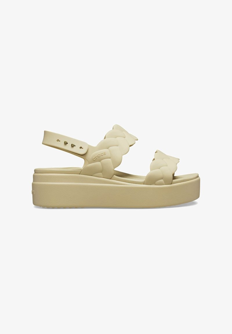 Sandale plateforme beige avec brides tressées et bride réglable à la cheville, dotée d'une semelle épaisse et d'un design à bout ouvert.