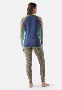 Long-sleeve athletic top in navy with floral patterned accents, paired with fitted leggings featuring vibrant yellow and blue floral designs.