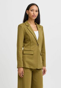 Olivovo zelený blazer s jedným gombíkom, s klopovými reverzami a dvoma prednými vreckami, prispôsobený strih, súčasť zladeného oblečenia.