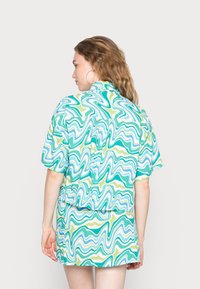 Conjunto de camisa de manga curta e saia com um padrão ondulado em verde-água, verde e branco. Tecido suave, ajuste relaxado e design com gola.