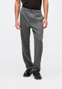 Sivi volneni hlače s ravnim krojem, sprednjim gumbom in stranskimi žepi. Ustrezajo črnimi mokasini.