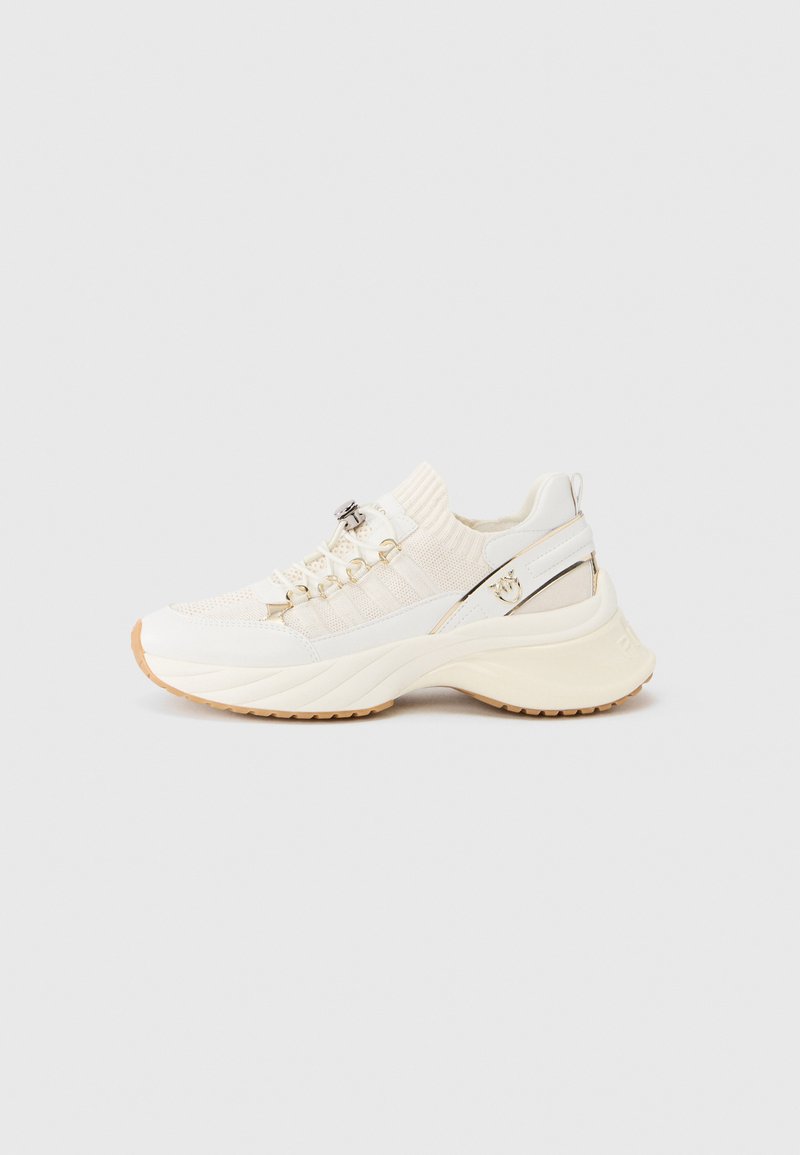 Λευκά πλεκτά αθλητικά παπούτσια με υφή στο πάνω μέρος, ελαστικό περιλαίμιο, μεταλλικές λεπτομέρειες και χοντρή σόλα με εξωτερική σόλα από καουτσούκ καραμέλας.