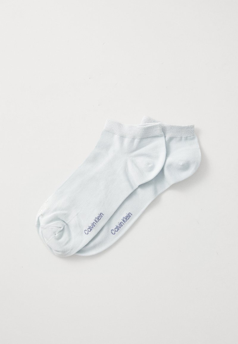Par de meias de tornozelo azul claro com o logótipo "Calvin Klein" impresso perto dos dedos em um fundo branco.