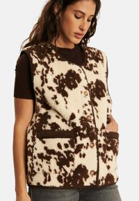 Fleece-Weste mit einem creme- und braunfleckigen Design, ausgestattet mit einer Knopfleiste, zwei Vorderaschen und einem runden Halsauschnitt.