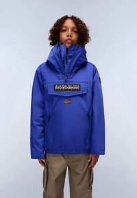 Blå vandtæt jakke med høj krave, lynlåslukning foran og stort logo-patch. Har et norsk flag-accent og sidelommer.