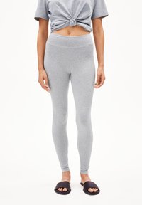 Gray cotton leggings with a smooth texture and high waist. Paired with a knotted short-sleeve gray top and black slide sandals.