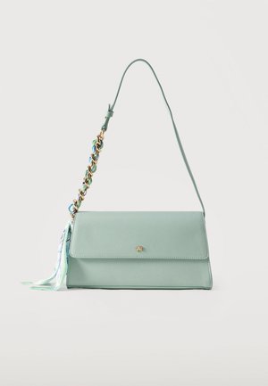 Sac bandoulière rectangulaire vert clair avec une bandoulière chaîne tressée multicolore et un pompon en tissu à motifs attaché.