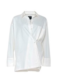 Hvit langermet skjorte i lett stoff. Med en frontlomme, knappelukking og en asymmetrisk nederkantsdesign.
