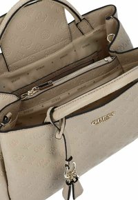 Borsa a mano in ecopelle beige con motivo testurizzato, hardware dorato, tasca con zip e un charm decorativo sul lato.